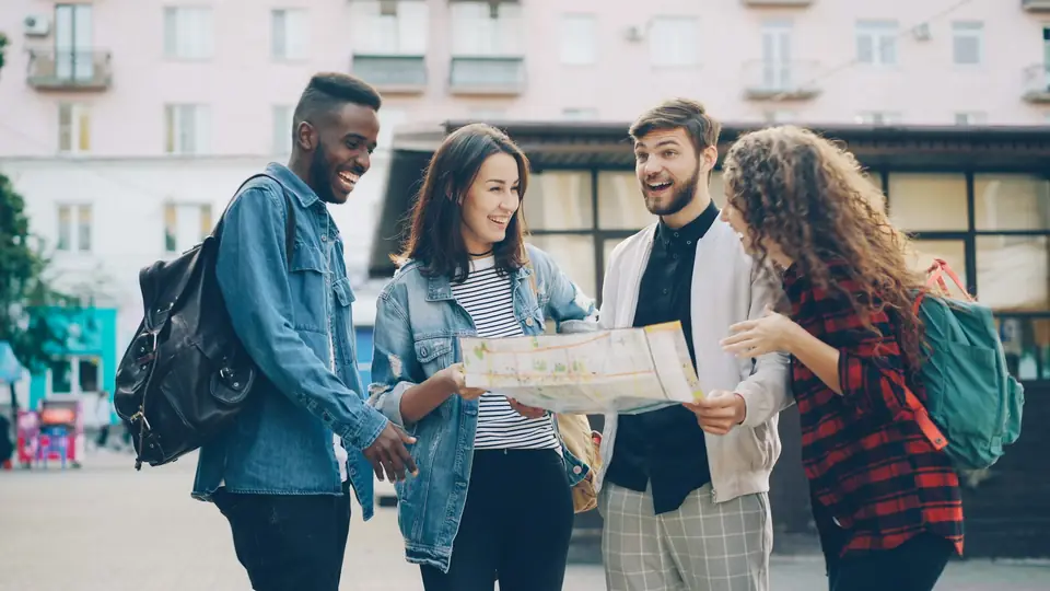 Grupo de amigos con mochilas consultando un mapa en una calle de la ciudad