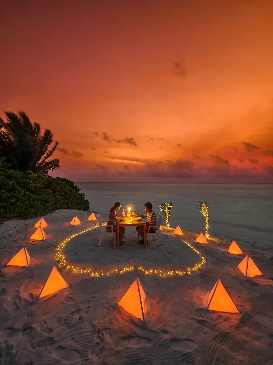Cena romántica en la playa al atardecer rodeada de velas